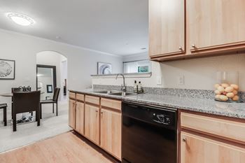 A kitchen with wooden cabinets and a black dishwasher.